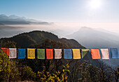 Bunte Gebetsfahnen vor einer weiten Berglandschaft am Fuße des Annapurna Circuit im Himalaya, Australian Camp, Nepal, Asien