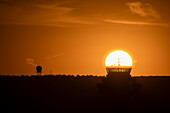 Die Sonne bei Sonnenaufgang, ausgerichtet auf einen Flughafenkontrollturm, Spanien, Europa