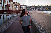 Woman at Promenade Jacques Thibaud boardwalk in front of the Grande Plage beach of Saint Jean de Luz,fishing town at the mouth of the Nivelle river,in southwest France’s Basque country