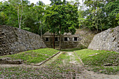 Ballspielplatz I auf der Plaza D der Maya-Ruinen im Yaxha-Nakun-Naranjo-Nationalpark, Guatemala. Struktur 389 in der südlichen Akropolis dahinter.