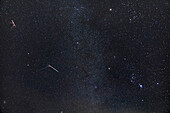 Der Geminiden-Meteorschauer von 2022, der zwei helle Geminiden zeigt, die gelbliche Ionenspuren oder "Rauch"-Züge in ihrem Kielwasser hinterlassen. Die beiden Meteore traten im Abstand von etwa 45 Minuten auf, sind hier aber miteinander verschmolzen.
