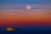 Die dünne, einen Tag alte Mondsichel knapp über Jupiter, als beide am Abend des 22. März 2023 untergehen. Das Leuchten des Erdscheins ist auf der dunklen Seite des Mondes deutlich zu sehen. Das Alter des Mondes betrug in dieser Nacht zu dieser Zeit und auf diesem Längengrad etwa 31,5 Stunden.