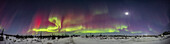 Ein 220°-Panorama eines farbenprächtigen Polarlichts in einer Kp6-Nacht am 26. Februar 2023 vom Churchill Northern Studies Centre, Churchill, Manitoba, auf 58° N. Der Blick geht hauptsächlich nach Süden über die alte Rocket Range, wobei der zunehmende Mond rechts im Stier in der Nähe der Plejaden und über Orion hervorsticht. Das Mondlicht beleuchtet den Vordergrund.