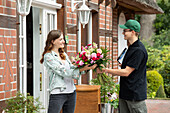 delivery service - supplier hands over bouquet of flowers
