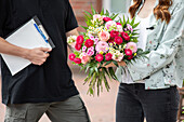 Delivery service - supplier hands over bouquet of flowers