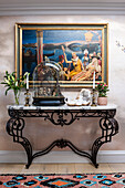 Ornamented French console with phalibois under glass bell jar, flanked by paintings