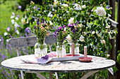 Vases with lavender and roses on a round wooden table in the summer garden