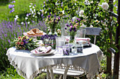 Laid garden table with lavender and bouquets of flowers in the summer garden