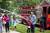 Firefighter demonstrating fire hose to children