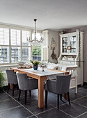 Dining room with wooden table, grey chairs and display cabinet in front of window with blinds