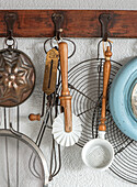 Vintage kitchen utensils hanging on wooden hook rail