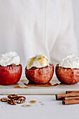 Baked apples with nut filling, topped with cream and maple syrup