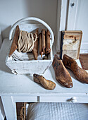 Rustic still life with wooden basket, spool and antique shoe moulds on white bedside table