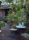 Cosy seating area in the garden with metal furniture and flower vases