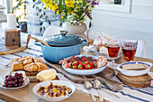 Lavishly laid breakfast table with fruit, pastries and blue roaster