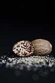 Whole nutmeg and freshly grated on a black background