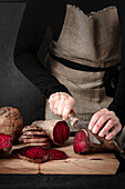 Woman slicing raw beetroot on a wooden board