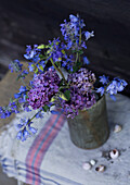 Bouquet of blue and purple flowers in tin vase on table