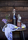 Glass bottles with syrup, lemon slices and lavender flowers on a rustic wooden stool