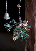 Weihnachtlicher Türschmuck aus Tannenzapfen, goldenen Eicheln und Glocke