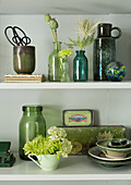 Decorative green vases and bowls with flower arrangement on shelf