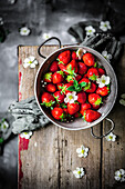 Strawberries in a metal sieve on a wooden table