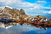 Blick über den natürlichen Fischereihafen auf die hoch aufragenden Berge über Reine, Moskenes, Insel Moskenesøya, Lofoten, Norwegen