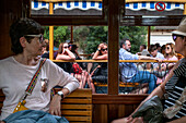 Touristen in der historischen Straßenbahn im Dorfzentrum von Soller. Die Straßenbahn verkehrt auf einer Strecke von 5 km zwischen dem Bahnhof im Dorf Soller und dem Puerto de Soller, Soller, Mallorca, Balearen, Spanien, Mittelmeer, Europa