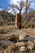 Eine Feuerstelle und ein Schornstein auf einer verlassenen Pionierranch in Cottenwood Glen im Nine Mile Canyon in Utah. Im Vordergrund ist der alte Wasserbrunnen zu sehen.