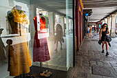 Eine Frau geht entlang der von Modegeschäften gesäumten Buchhändlerstraße in Alcala de Henares Madrid Spanien