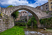 Ancient and modern: a road bridge now spans the Llobregat river at La Pobla de Lillet in Catalonia, Spain, beside the medieval Pont Vell or Old Bridge, built in the 1300s AD. The Pont Vell now has a single high donkey back arch, but there may once have been a second arch and the ashlar foundations of the pillars suggest Roman origins