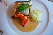 A dish of hake cabbage and prawns served in the art deco restaurant wagon of the train Belmond Venice Simplon Orient Express luxury train.