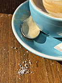 Sugar spilled next to coffee on table