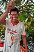 Pacaya Samiria Reservat, Peru, Südamerika. Mann zeigt die scharfen Zähne eines Roten Piranhas, der im Fluss Ucayali im Amazonasbecken gefangen wurde