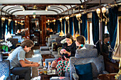 Customers in the art deco bar lounge wagon of the train Belmond Venice Simplon Orient Express luxury train.