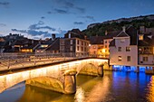 France, Doubs, Loue valley, village of Ornans, mirror of the Loue at dusk and the large illuminated bridge