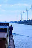 Frankreich, Bouches du Rhone, Port Saint Louis du Rhone, Containerschiff und Conqueror Pusher (CFT) auf dem Rhonekanal bei Fos, ein Segler, im Hintergrund Windräder