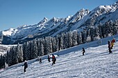 Frankreich, Haute Savoie, La Clusaz, Skifahrer auf den Pisten des Crêt du Merle und den Gipfeln des Aravis-Massivs