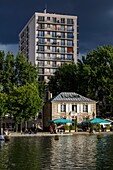 France, Paris, La Villette, Villette channel, view of the street animation of the quays of the canal of La Villette under a sky of storm