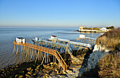 France, Charente Maritime, Saintonge, Gironde Estuary, Saintonge,Talmont sur Gironde, labelled Les Plus Beaux Villages de France (The Most Beautiful Villages of France), huts on stilts for Carrelet (fisherman's hut) fishing net, in the background Sainte Radegonde church in Saintonge Romanesque style of the 12 th century