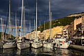 France, Corse du Sud, Bonifacio, sailboats in the marina at sunset under stormy sky