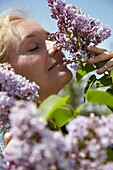 Woman smelling Syringa shrub