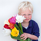 Junge mit Frühlingsblumen in der Hand