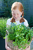 Girl holding basket with mixed herbs