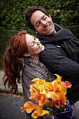 Couple riding bicycle holding flowers