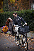 Fahrradfahrendes Paar mit Blumen in der Hand