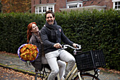 Couple riding bicycle holding flowers