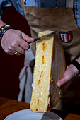 Man scraping swiss traditional melted Raclette cheese