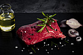 Raw, lightly marbled beef steak with pepper, salt and rosemary