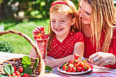 Frau und kleines Mädchen essen frische Erdbeeren